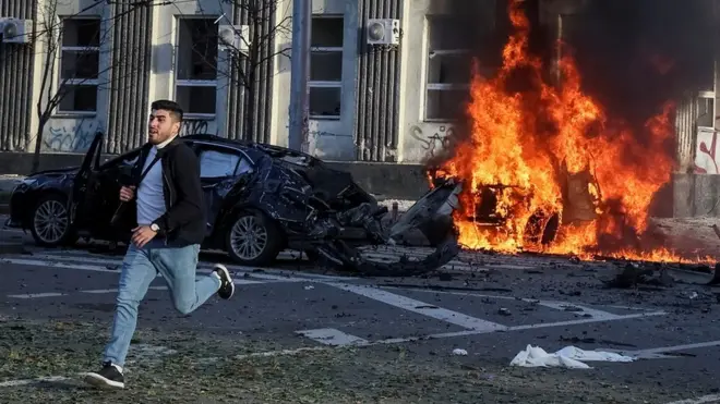 A man flees as cars burn after Russian military strike in central Kyiv, Ukraine 10 October 2022.