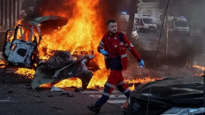 Un rescatista frente a un auto incendiado en Kyiv