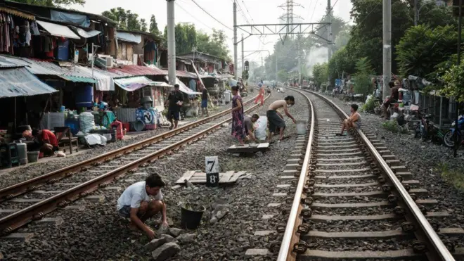 Warga yang tinggal di sepanjang jalur kereta api melakukan aktivitas di tengah rel di Jakarta pada 12 Mei 2024.