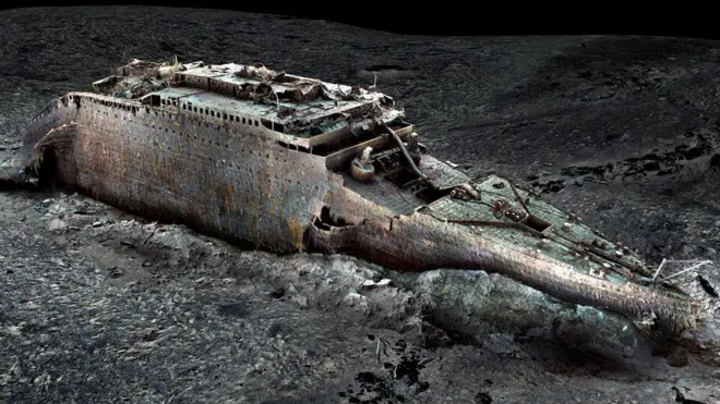 A digital replica of the bow section of the Titanic is sitting upright on the ocean floor. The back of the section, which is in the top left corner, is ragged while the front of the ship, at the bottom right of the image is instantly recognisable. The ship is a ghostly grey and the hull is damaged from where it slid into the mud and jackknifed as it became more embedded in the silt. There's a big gash where the flat deck at the front of the ship rises up to the higher decks and the bridge of the ship.