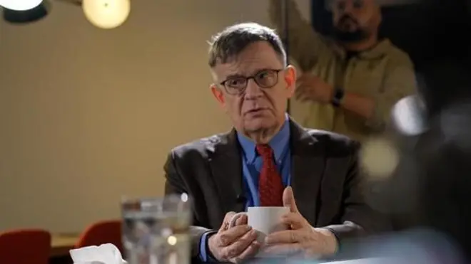 Андрей Ланьков сидит с чашкой во время съемки