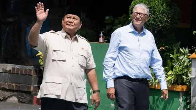 Presiden Prabowo Subianto (kiri) dan pendiri Microsoft, Bill Gates, (kanan) melambaikan tangan ke arah siswa-siswa saat meninjau pelaksanaan program Makan Bergizi Gratis (MBG) di SDN 03 Jati Pulogadung, Jakarta, Rabu (07/05).