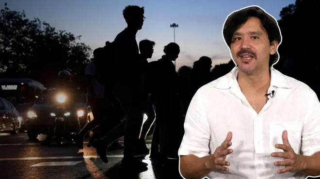 Repórter Shin Suzuki diante de imagem de pessoas caminhando na escuridão na Espanha