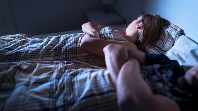 Parejas en una cama, cada uno con los brazos cruzados