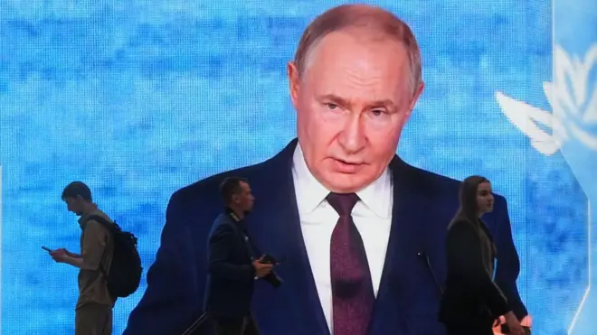 Люди проходять повз екран із зображенням Володимира Путіна на Міжнародному економічному форумі в Санкт-Петербурзі, 3 червня 2026 року. 