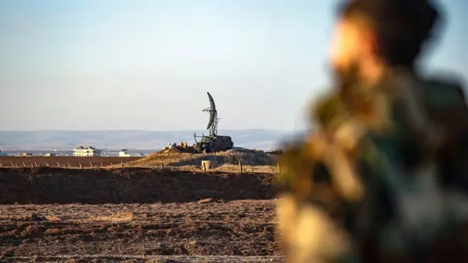 مقاتلون من قوات سوريا الديمقراطية يقفون حراسًا أمام رادار مهجور في مطار القامشلي الدولي، والذي كان في السابق قاعدة عسكرية سورية روسية مشتركة، في مدينة القامشلي شمال شرق سوريا 