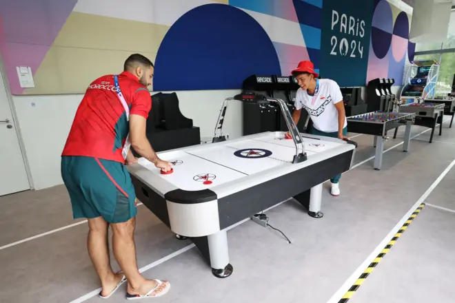 Two athletes from Team Morocco play air hockey at a social room of the Athletes's Village.