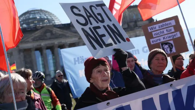 Kadınlar "hayır" yazan pankartlar taşıyor, arkada Almanya parlamento binası