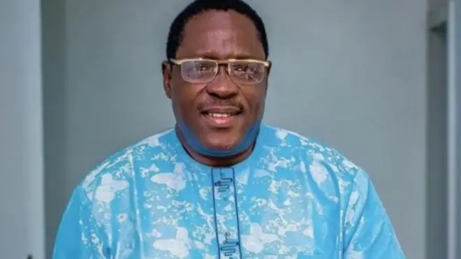 Taiwo Hassan lo igo soju, o si wọ aṣọ olomi buluu to ni funfun bii labalaba ninu, bẹẹ lo fi igo soju