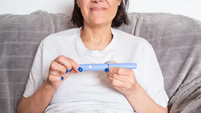 سيدة تمسك بيدها حقنة إنقاص الوزن