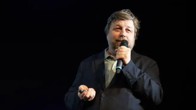 Чоловік у темному костюмі з мікрофоном 