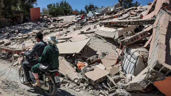 Homem e mulher,betano lmoto,betano lfrente a prédio destruído