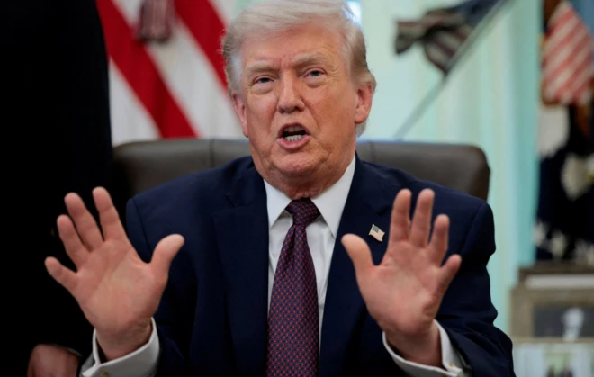 ABD Başkanı Donald Trump oval ofisteki masasında oturuyor ve ellerini kendisine özgü şekilde iki yana açmış