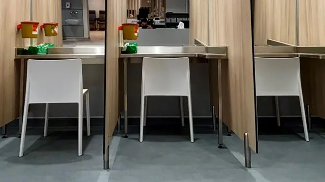 Close up of three booths, with white chairs against a mirrored back wall