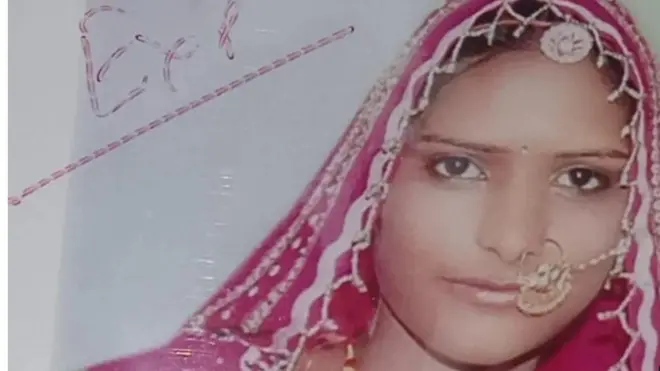 Aworan yii ṣafihan Lakshmi, obinrin to pade iku ojiji lọwọ ọkọ rẹ nitori ko pupa bii oyinbo. Lakshmi fi ibori pupa bo ori rẹ, o si lu imu rẹ pẹlu yẹti oloruka kan. O n wo orere pẹlu oju rẹ to gun rege.