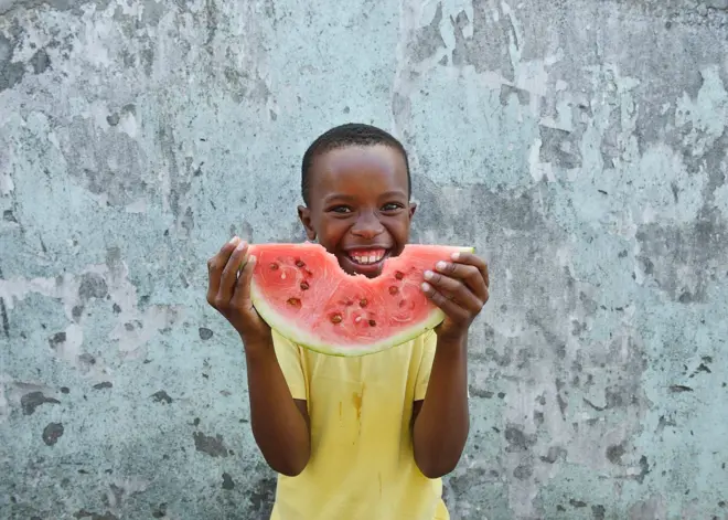 Un enfant mange une tranche de pastèque