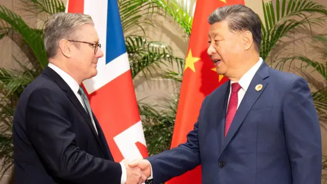 Prime Minister Sir Keir Starmer shaking hands with President Xi Jinping in front of a British and Chinese flag.