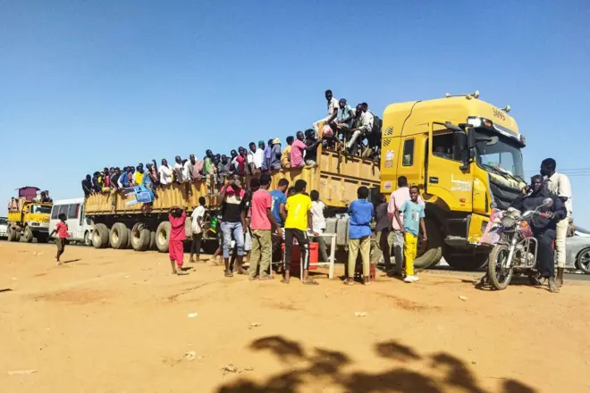 People displaced by the conflict in Sudan get on top of the back of a truck moving along a road in Wad Madani, the capital of al-Jazirah state, on 16 December, 2023