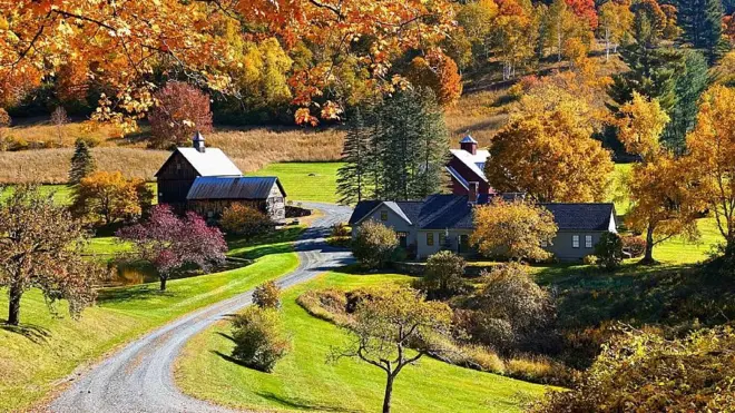 Granja rodeada de árboles con colores otoñales