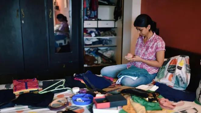 Woman checks mobile while organising wardrobe