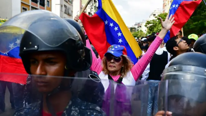 A supporter of self-proclaimed acting president Juan Guaidó, demonstrates behind a line of police officers in Caracas on March 9, 2019