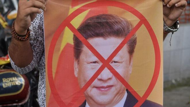 Protestor in Delhi holding picture of Xi Jinping