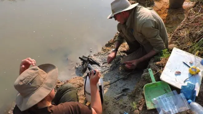 Larry Barham (photo, à droite) explorant une structure en bois au bord de la rivière