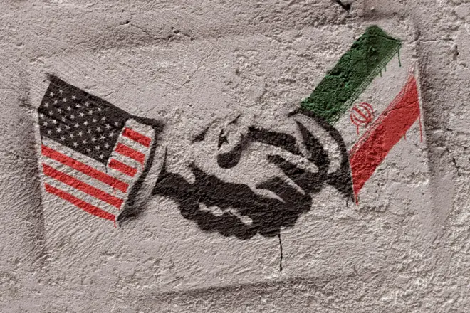 گرافیتی پرچم ایران و آمریکا روی دیوار که در حال دست دادن با هم هستند