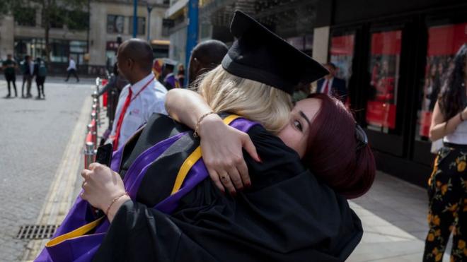 Dos graduadas se abrazan.
