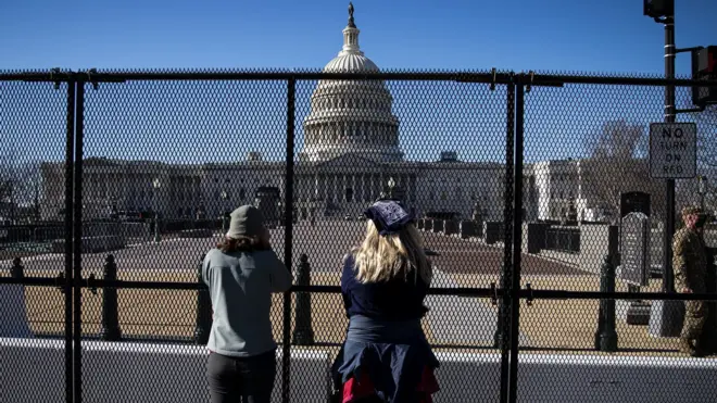 People view the U.S. Capitol, behind security fencing