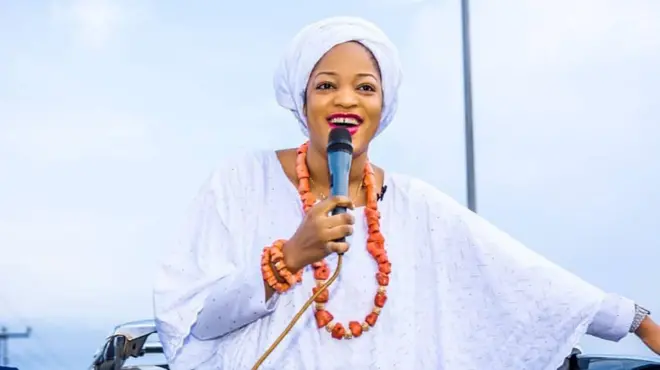 Queen Naomi speaking into a microphone