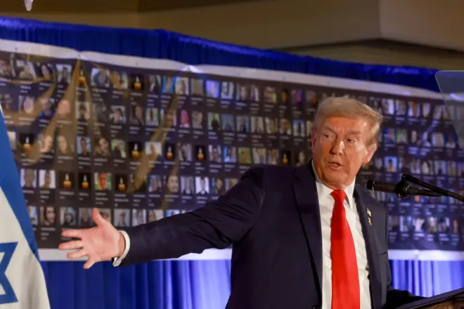 صورة سابقة للرئيس الأمريكي دونالد ترامب، خلال فعالية إحياء ذكرى السابع من أكتوبر/ تشرين الأول في نادي ترامب الوطني للغولف في فلوريدا، ويظهر خلفه صور لرهائن في غزة