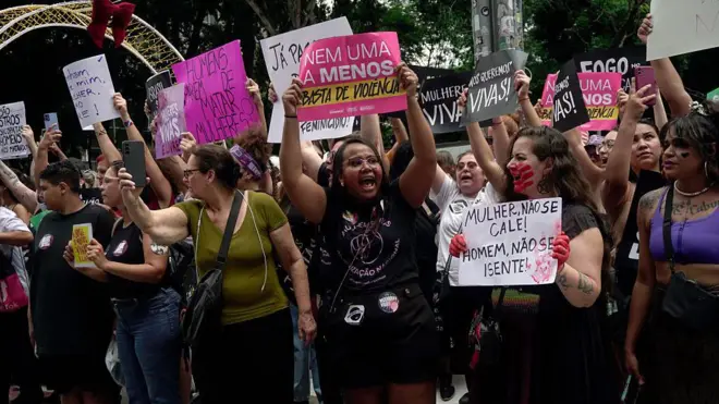 Grupo de mulheres levantando cartazes durante manifestação contra o feminicídio em dezembro de 2025.