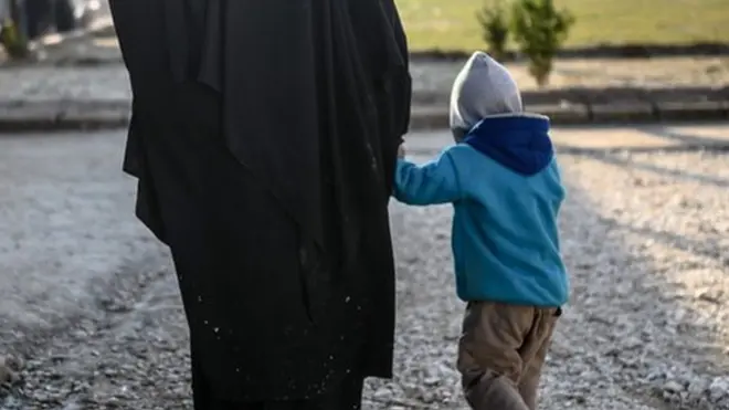 A Frenchwoman walks with her child in a camp in Northern Syria