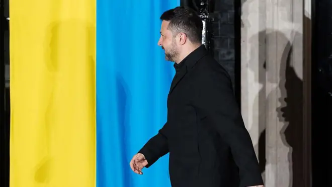 Зеленський йде на фоні українського прапору 