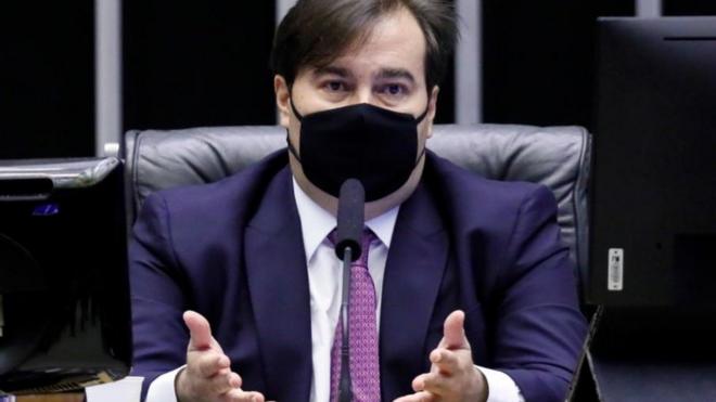 Maiapoker 4 cartascadeira na mesa da Câmara, sentado, com máscara e gesticulando ao falar no microfone