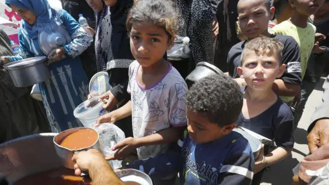 Niños hacen cola en un reparto de comida. 