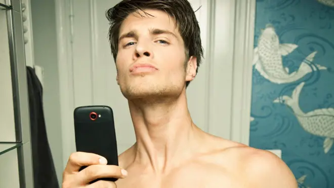 Homem jovem tirando uma foto no espelho