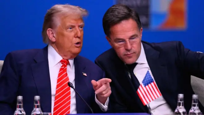 Donald Trump in a dark suit, white shirt and red tie speaks to NATO Secretary General Mark Rutte