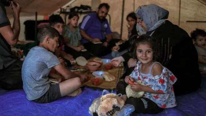 A Palestinian family sits inside a tent, enjoying lunch in a refugee camp in Khan Yunis on October 20, 2023.