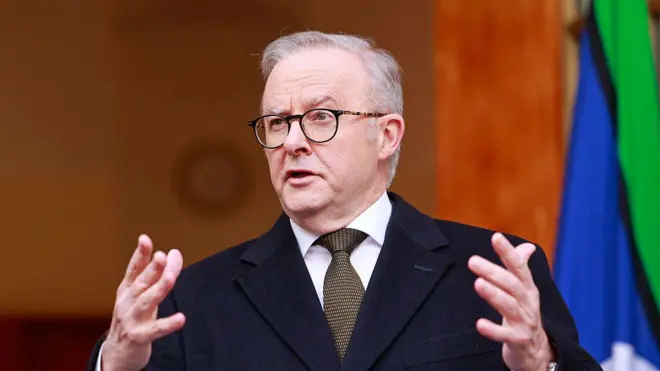 رئيس الوزراء الأسترالي أنتوني ألبانيز يتحدث خلال مؤتمر صحفي في كانبيرا في 11 أغسطس/آب 2025. يرتدي بدلة رسمية كحلية اللون ويحرك يديه أثناء حديثه وخلفه العلم الأسترالي.