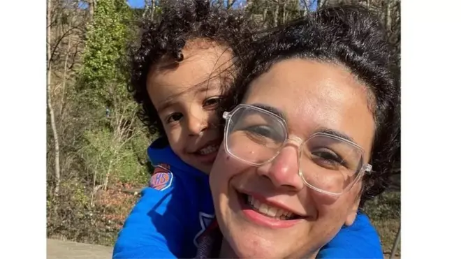 Mai qui porte son enfant sur les épaules