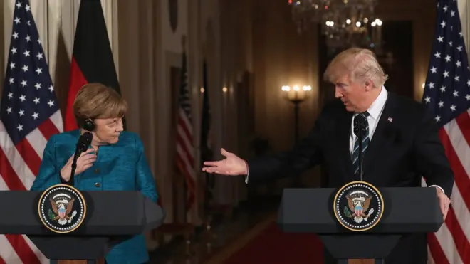 Angela Merkel menatap Trump, ketika Presiden AS itu menyampaikan klaim dia dan Merkel disadap Obama.