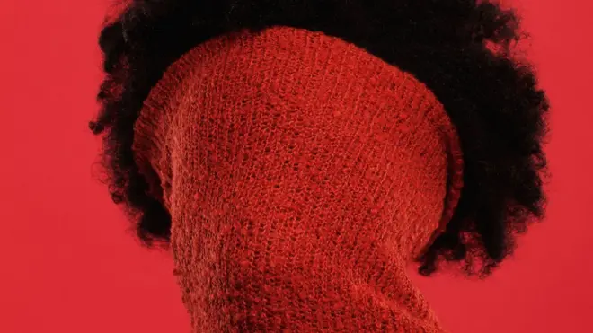 Une femme avec le visage couvert par un pull