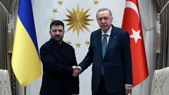 Zelenskiy ve Erdoğan ayakta el sıkışırken, arkalarında iki ülkenin bayrakları ve aralarından görülen duvarda da Cumhurbaşkanlığı Forsu görülüyor
