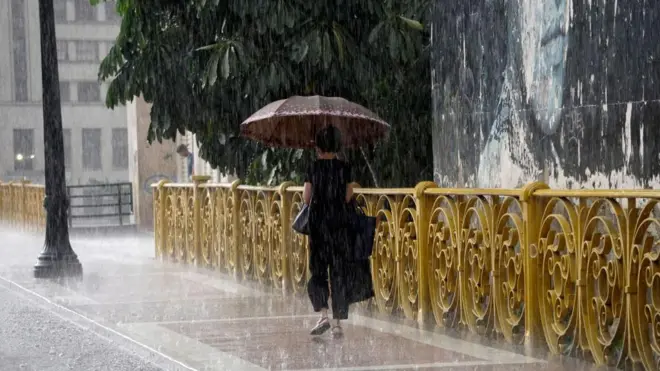 Pessoa usando guarda-chuva durante tempestade