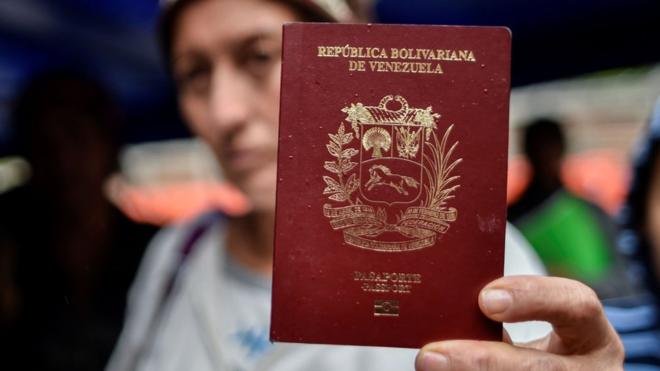 Mujer enseñando su pasaporte venezolano.
