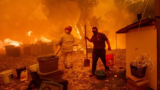 Resident Lane Lawder carries a water bucket while fighting to save his home from a fire in northern California