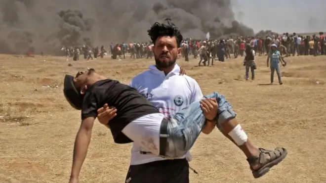 Uno de los manifestantes carga a otro que fue herido durante las protestas de este lunes en la frontera con Gaza.