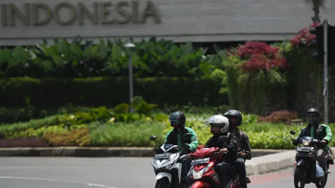 Pengendara motor melintas tanpa menggunakan masker dan berboncengan di kawasan Bundaran HI, Jakarta, Kamis (16/4). Meskipun DKI Jakarta telah menerapkan aturan berkendara di masa Pembatasan Sosial Berskala Besar (PSBB) seperti keharusan menggunakan masker maupun larangan berboncengan, tapi masih banyak ditemukan pelanggaran-pelanggaran tersebut di jalan raya.